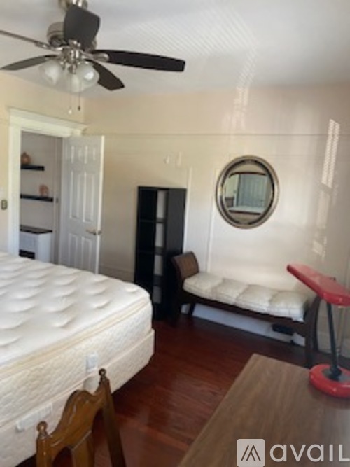 A bedroom with a bed, a bench, and a ceiling fan.