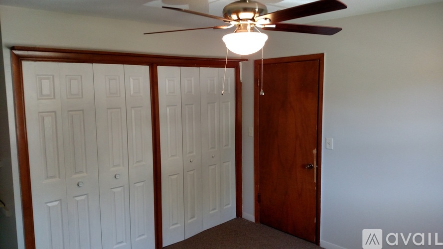A room with a ceiling fan and a door.