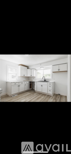 A kitchen with white cabinets and a wooden floor.