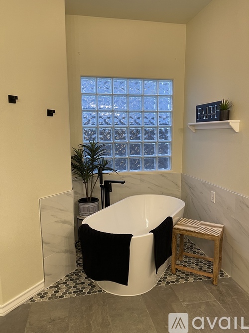 A bathroom with a black and white bathtub, a potted plant, and a window with a view of a building.