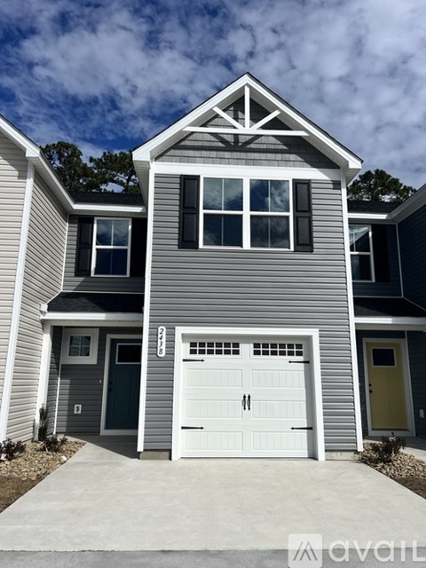 A two-story house with a garage door and a driveway in front.