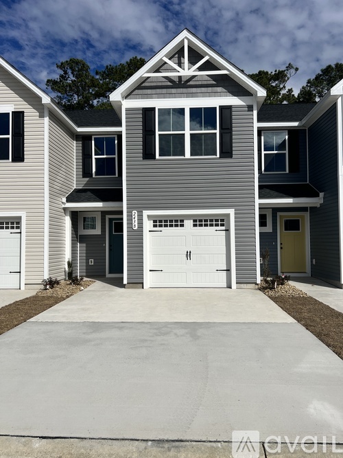 A modern house with a grey and white exterior and a large driveway.