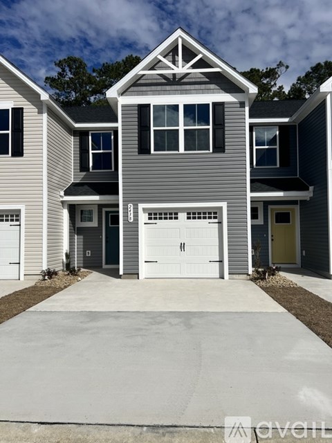 A modern house with a grey and white exterior and a large driveway.