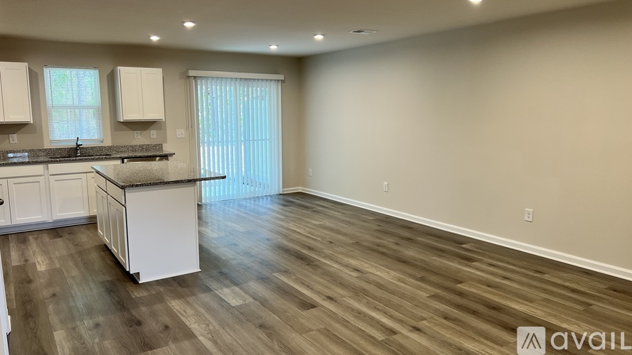 A kitchen with white cabinets and a wooden floor.
