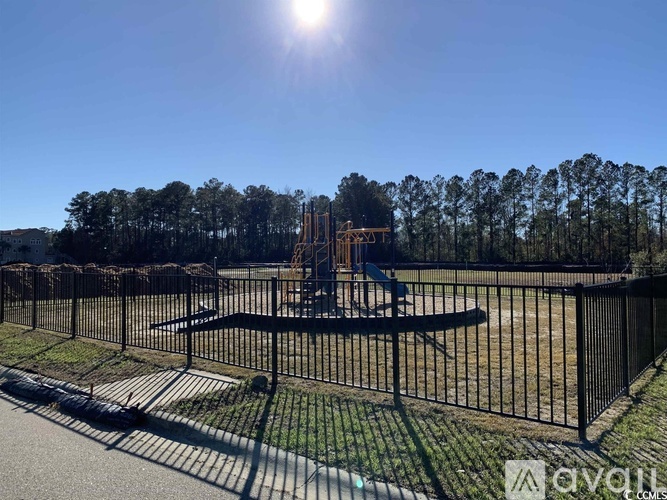 A playground with a swing set and a fence in the foreground.
