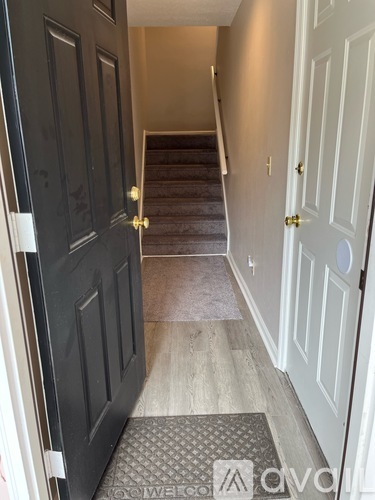 A hallway with a black door on the left and a white door on the right.