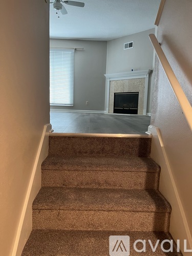 A staircase with a carpeted runner and a fireplace in the background.