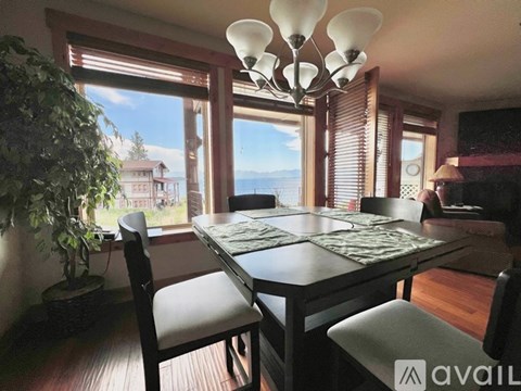 A dining room with a table and chairs and a view of the water.