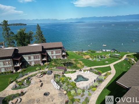 A large house with a pool and a garden in front of a lake.