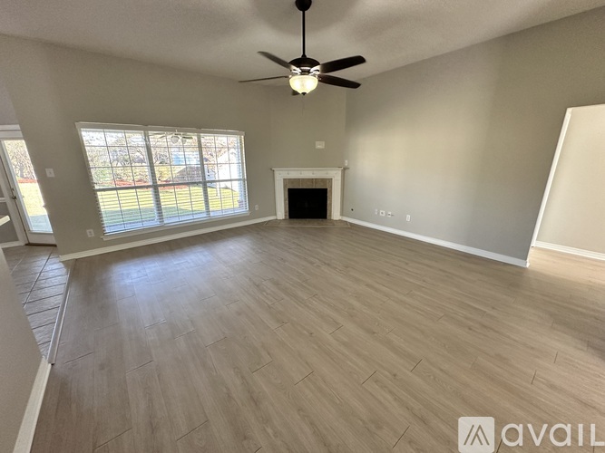 A spacious room with a fireplace and a ceiling fan.
