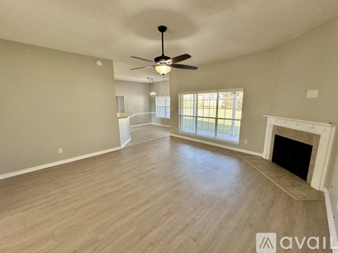 A spacious living room with a fireplace and a ceiling fan.