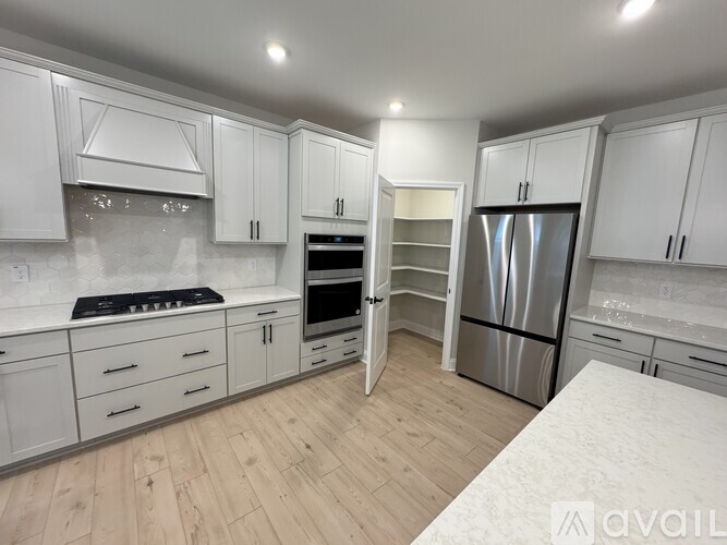 A kitchen with white cabinets and a wooden floor.