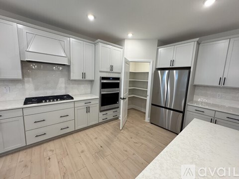 A kitchen with white cabinets and a wooden floor.