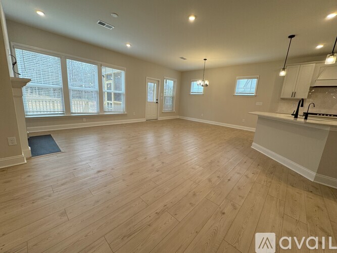 A spacious room with wooden flooring and large windows.
