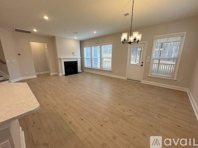 A spacious living room with wooden flooring and a fireplace.