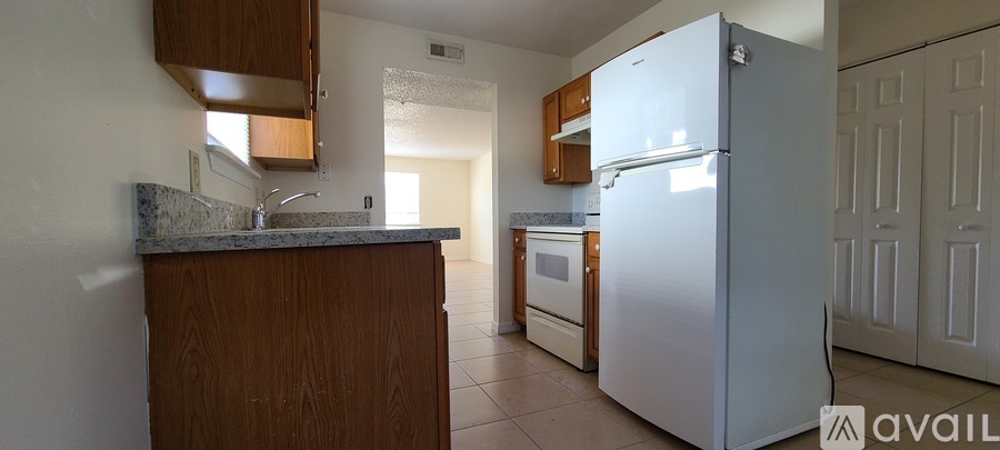 A kitchen with a white refrigerator and wooden cabinets.