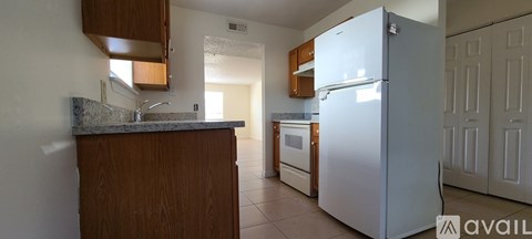 A kitchen with a white refrigerator and wooden cabinets.