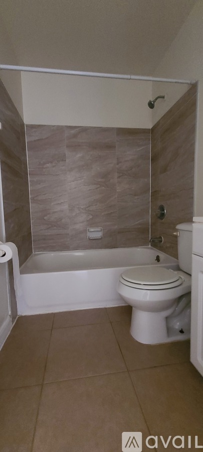 A bathroom with a toilet, tub, and tiled walls.