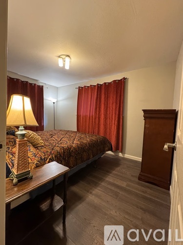 A bedroom with a bed, nightstand, and a lamp.