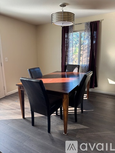 A dining room with a wooden table and black chairs.