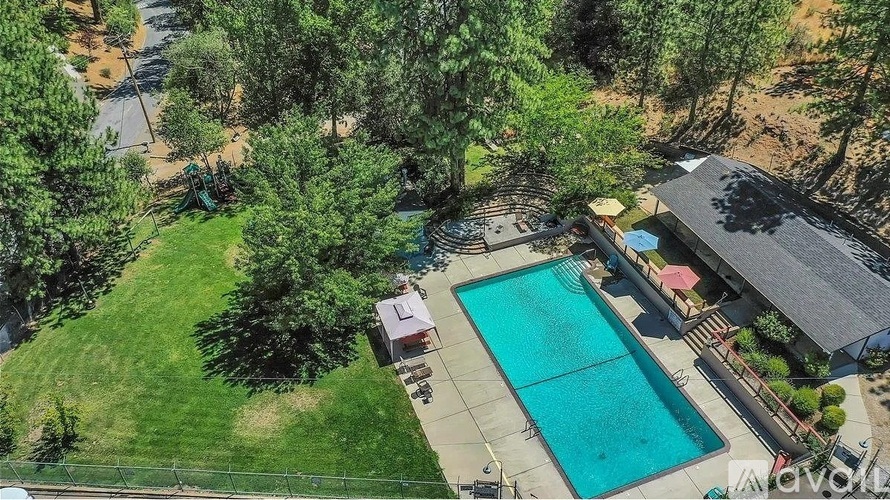 An aerial view of a house with a pool surrounded by trees.