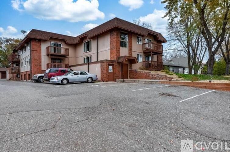 A parking lot in front of a two-story apartment building with cars parked.