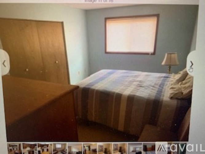 A bedroom with a bed, nightstand, and a window with blinds.