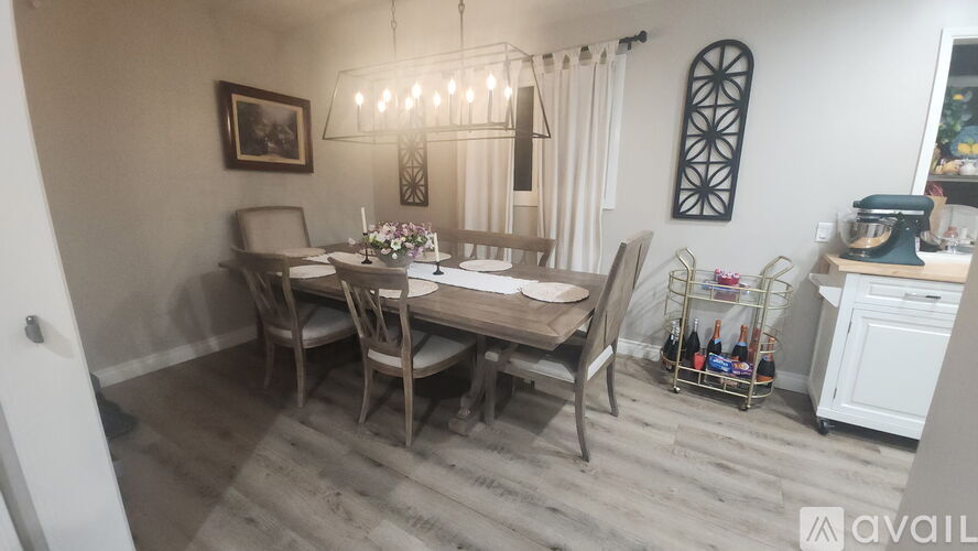 A dining room with a table set for four and a chandelier hanging from the ceiling.