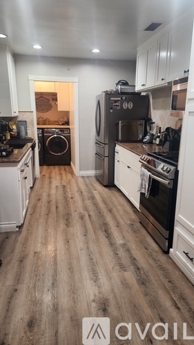 A kitchen with a black refrigerator and wooden floors.