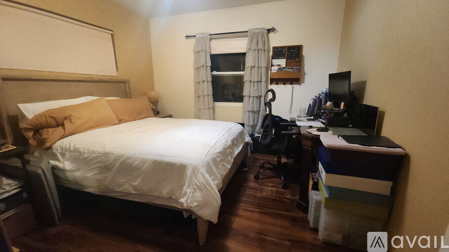 A bedroom with a bed, desk, and chair.