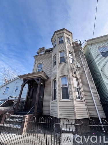 A two-story house with a balcony and a fence in front.