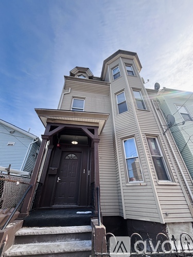 A two-story house with a black front door and stairs leading up to it.