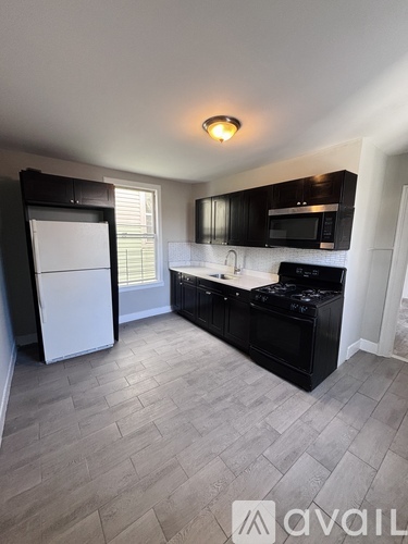 A kitchen with black cabinets and a white refrigerator.