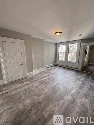 A room with a wooden floor and a window with a view of trees.