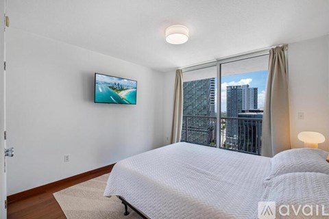 A bedroom with a large bed and a flat screen TV mounted on the wall.