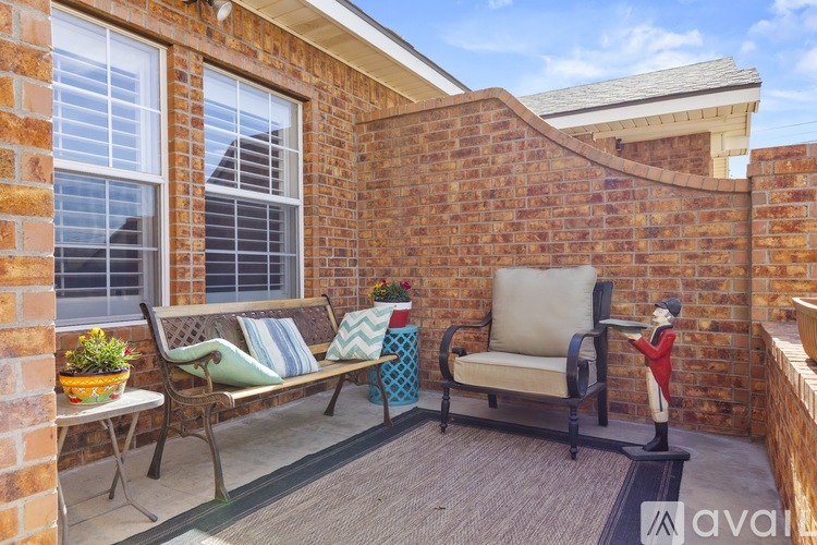 A patio with a bench, cushions, a chair, and a potted plant.