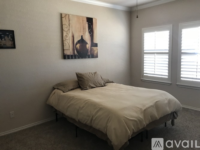 A bedroom with a bed, pillow, and a painting on the wall.