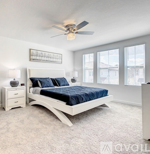 A bedroom with a white bed and a ceiling fan.