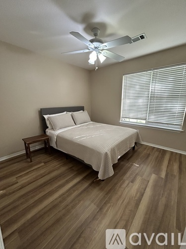A bedroom with a bed, a ceiling fan, and a window with blinds.