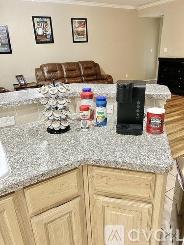 A kitchen counter with a variety of items including a coffee maker, a jar of peanut butter, and a stack of canned goods.