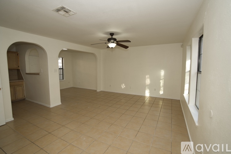 A spacious room with a ceiling fan and tiled flooring.