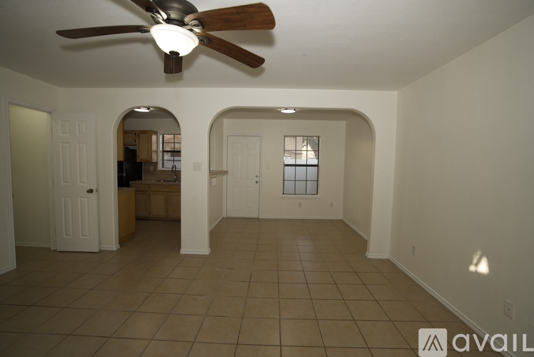 A spacious room with a ceiling fan and arched doorways.