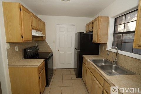 A kitchen with wooden cabinets and a black refrigerator.