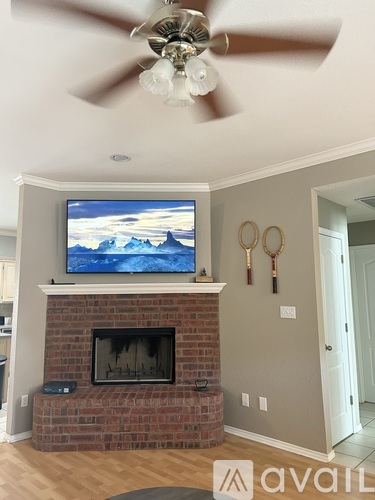 A living room with a television on a brick fireplace.