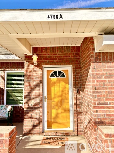 A house with a yellow door and a sign that says "Welcome 1911 Home".