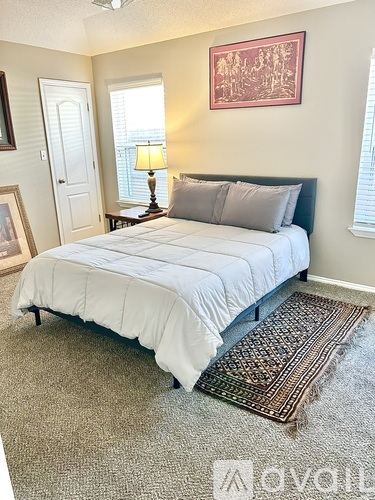 A bedroom with a bed, lamp, and framed picture on the wall.