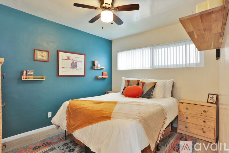 A bedroom with a bed, dresser, and ceiling fan.