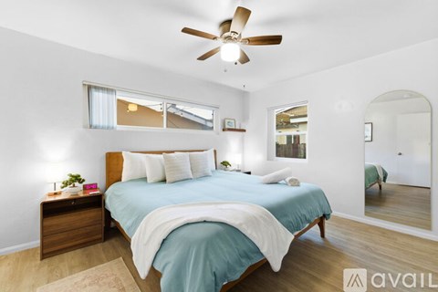 A bedroom with a bed, dresser, and ceiling fan.