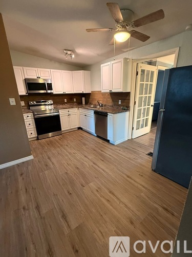 A kitchen with wooden floors and a ceiling fan.