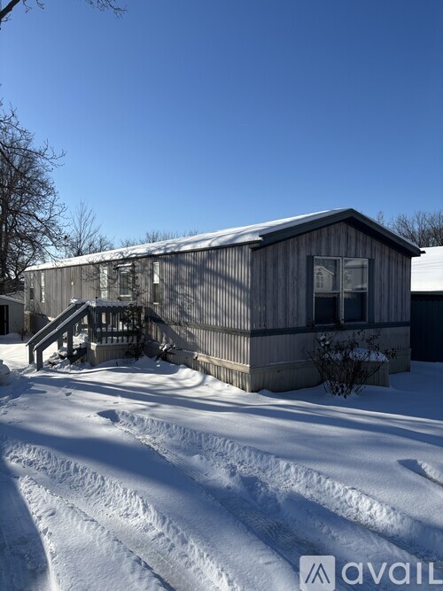 A wooden building with a snow-covered roof and a small tree in front.